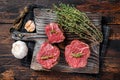 Prime raw Fillet mignon steaks on a wooden board with thyme and garlic. Dark wooden background. Top view