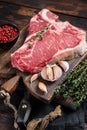 Prime T-bone beef meat steak, raw porterhouse steak on butcher board with herbs. Wooden background. Top view Royalty Free Stock Photo