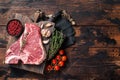 Prime T-bone beef meat steak, raw porterhouse steak on butcher board with herbs. Wooden background. Top view. Copy space Royalty Free Stock Photo