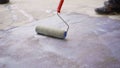 Priming the concrete floor with a roller. Professional floor primer. Leveling concrete floors. Floor repair using a primer Royalty Free Stock Photo