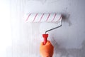 Priming the wall with roller, hand in glove close-up