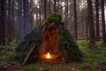 Primitive Bushcraft Shelter with campfire in the Wilderness. Royalty Free Stock Photo