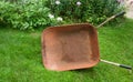 Primitive Red Wheelbarrow Sidewise on Grass and Garden