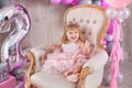 Princess baby girl celebrating life event wearing golden crown and pink airy dress. Cute girl posing in pastel colors studio shoot