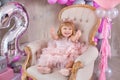 Princess baby girl celebrating life event wearing golden crown and pink airy dress. Cute girl posing in pastel colors studio shoot