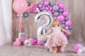 Princess baby girl celebrating life event wearing golden crown and pink airy dress. Cute girl posing in pastel colors studio shoot