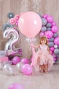 Princess baby girl celebrating life event wearing golden crown and pink airy dress. Cute girl posing in pastel colors studio shoot