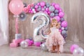 Princess baby girl celebrating life event wearing golden crown and pink airy dress. Cute girl posing in pastel colors studio shoot