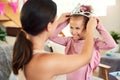 A princess needs her crown. a mother putting a crown on her daughters head during her birthday at home. Royalty Free Stock Photo