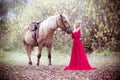 Princess in red dress with horse in fall, autumn. Fairy tale, fantasy.