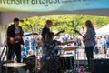 Musical group is seen from the back as they play their instruments in front of a crowd at an outdoor fair. There is a woman Royalty Free Stock Photo