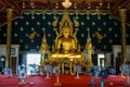 Principal buddha image in shinning golden color sitting in the decorative main hall with apostle monk image standing on both sides