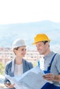 Principal and builder reading blueprints on construction site