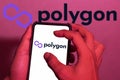 Hand close-up. This photo illustration displays a polygon logo (MATIC) on a cellphone screen