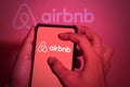 Hand close-up. This photo illustration shows the airbnb logo on a phone screen. clippingpath