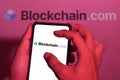 Hand close-up. This photo illustration shows the Blockchain logo on a cellphone screen