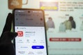 close up of human hand, uniqlo app id icon on smart phone screen close up