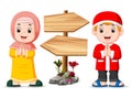 the two muslim children are standing near the wooden signpost Royalty Free Stock Photo
