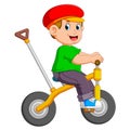 The boy is cycling on the yellow bicycle with the holder