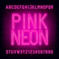 Pink Neon alphabet font. Light bulb letters and numbers on brick wall background. Royalty Free Stock Photo