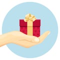 Gift in a red box with a golden bow in hand. Hand holds a present. Royalty Free Stock Photo