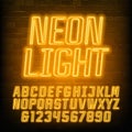 Neon alphabet font. Yellow neon geometric letters and numbers. Brick wall background.