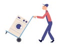Full length profile shot of a delivery man pushing a hand truck loaded with a washing machine isolated on white background