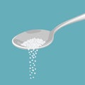 Salt pouring from a metal spoon isolated on a blue background.