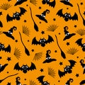 Witch hat, bat, spider web, and broom hand drawn seamless pattern on orange color background for Halloween. Royalty Free Stock Photo