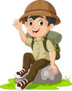 Cartoon boy scout sit on the rock waving hand Royalty Free Stock Photo