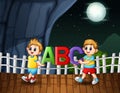 Happy boys holding ABC letter in the night landscape Royalty Free Stock Photo