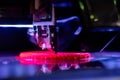 Print head of 3D printer machine printing flat plastic model - close up