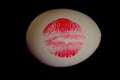Print of red lips on white egg. Red lip imprint on easter egg on black background. Royalty Free Stock Photo
