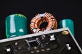 Printed circuit board with toroidal coil or green capacitors on black background