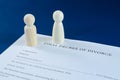 Printed decree of divorce with man and woman wooden figurines standing apart