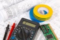 Printed drawings of electrical circuits, digital multimeter, electronic board and insulating tape.