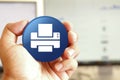 Printer icon blue round button holding by hand infront of workspace background