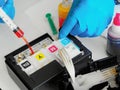 Printer maintenance. Master fills inkjet printer with ink or syringe paint. Hands with gloves close-up. Royalty Free Stock Photo