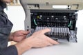 printer repair technician. A male handyman inspects a printer before starting repairs in a client's apartment.