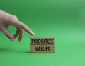 Prioritize values symbol. Concept word Prioritize values on wooden blocks. Beautiful green background. Businessman hand. Business Royalty Free Stock Photo