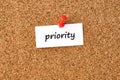 Priority. Word written on a piece of paper, cork board background Royalty Free Stock Photo