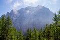 Prisojnik or Prisank ridge with morning misty clouds, as seen from the forest below, at the beginning of the via ferrata route Royalty Free Stock Photo