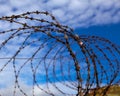 Prison. Barbed wire. Barbed wire on blue sky background with white clouds. Wire boom. Military conflict . Syria. Royalty Free Stock Photo