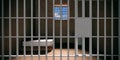 Prison cell interior. Locked door closeup, dark jail room background. 3d illustration