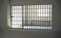Prison cell interior with locked door and light shining through window Royalty Free Stock Photo