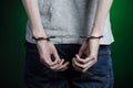 Prison and convicted topic: man with handcuffs on his hands in a gray T-shirt and blue jeans on a dark green background in the stu Royalty Free Stock Photo