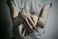 Prison and convicted topic: man with handcuffs on his hands in a gray T-shirt on a gray background in the studio, put handcuffs on