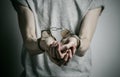 Prison and convicted topic: man with handcuffs on his hands in a gray T-shirt on a gray background in the studio, put handcuffs on