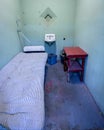 Prison inmates jail cell bed and sink with blue painted walls
