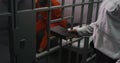 Prison officer gives Bible to male prisoner in orange uniform Royalty Free Stock Photo